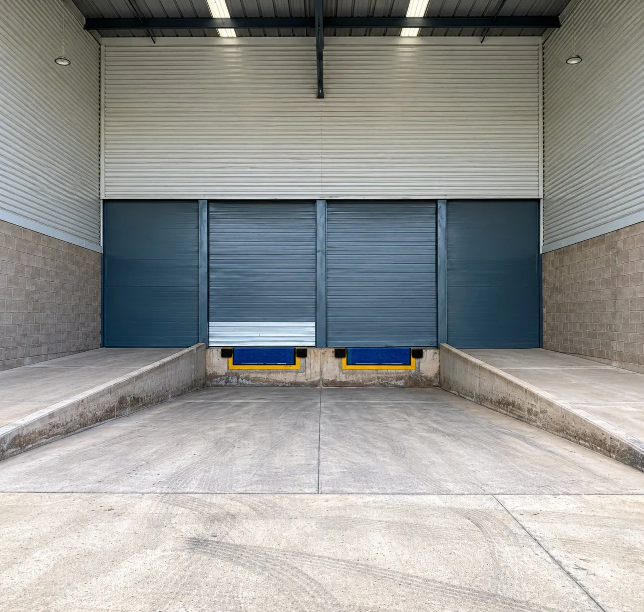 Andén techado de una bodega de Pocket Park con dos cortinas, rampas niveladoras y rampa de concreto