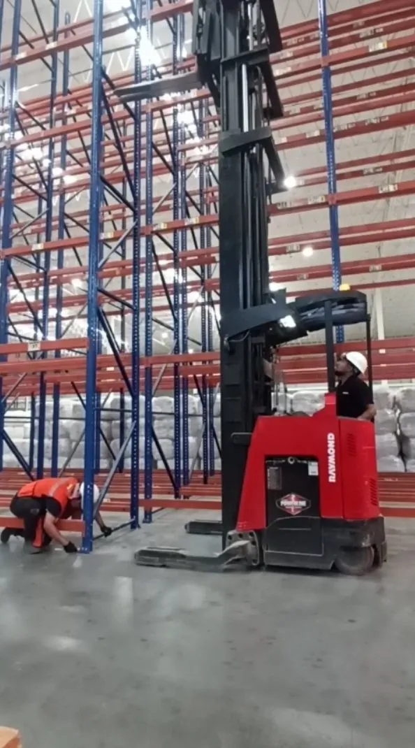 Instalador de ML Racks nivelando la base de un marco junto a un montacargas de pasillo angosto